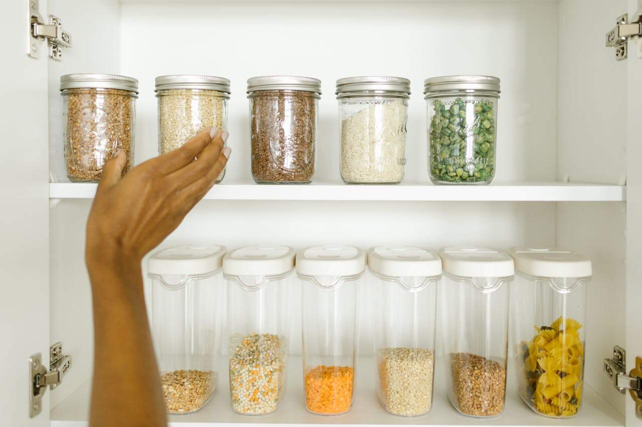 A neat pantry shelf showing various grains stored in labeled glass and plastic containers, promoting kitchen organization.